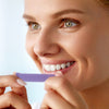 Sbiancamento dei denti con strisce sbiancanti viola sui denti di una donna
