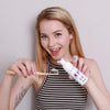 Donna con schiuma sbiancante Diamond Smile e spazzolino da denti in mano